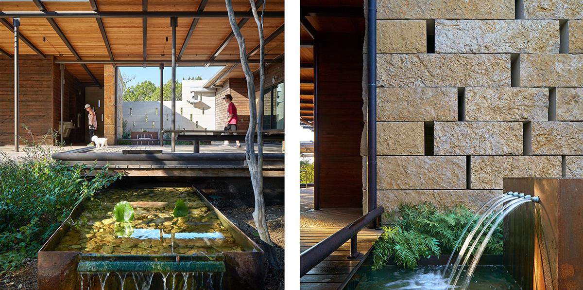 Wood and steel canopy over an outdoor wood deck surrounded by stone walls and water features. 