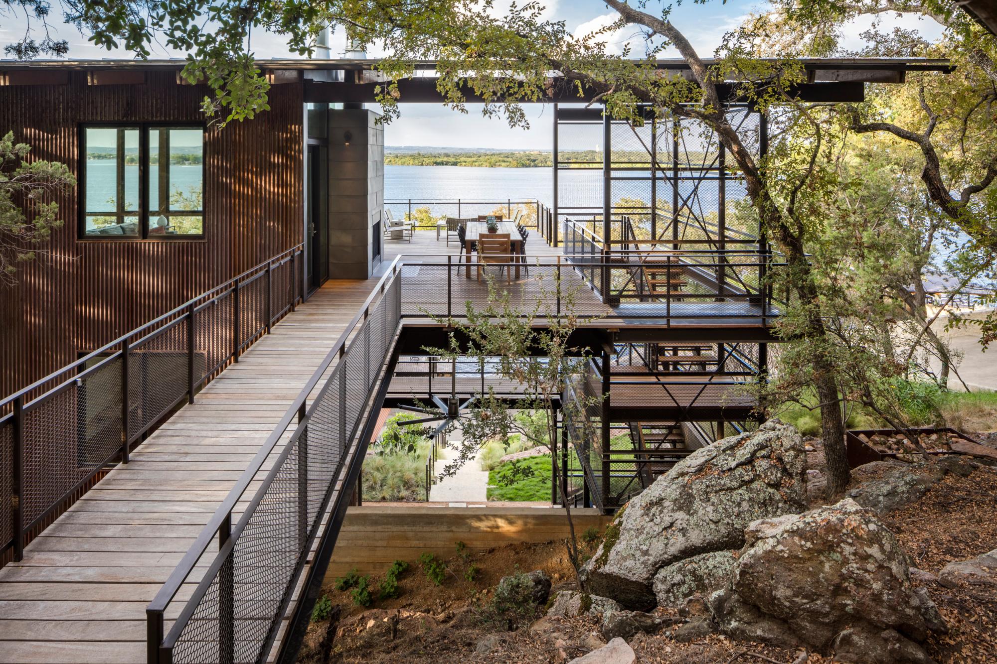 An award winning lake house featuring a bridge that anchors the home into the hillside, connecting it to the surrounding landscape.