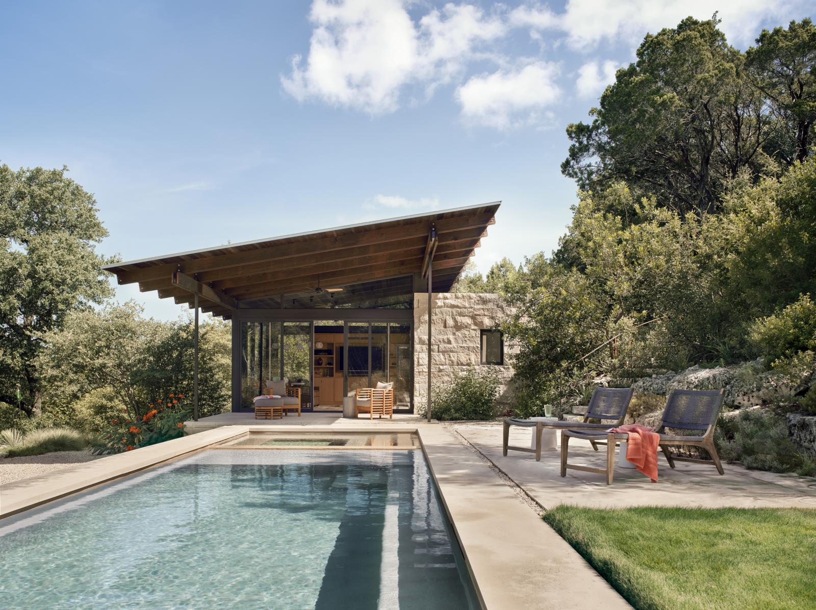 Pool and stone pool house beyond The linear plans of the pool house are comprised of a simple stone “box” of rooms that anchor the structures to the hillside