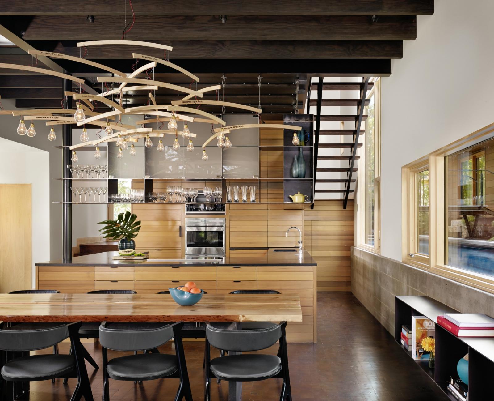 Situated at the confluence of Hog Pen Creek and Lake Austin, Hog Pen Creek Residence was envisioned by its owners as a place that evokes the playfulness of summer on the lake. Interior image looking across custom wood dining table and chandelier with view