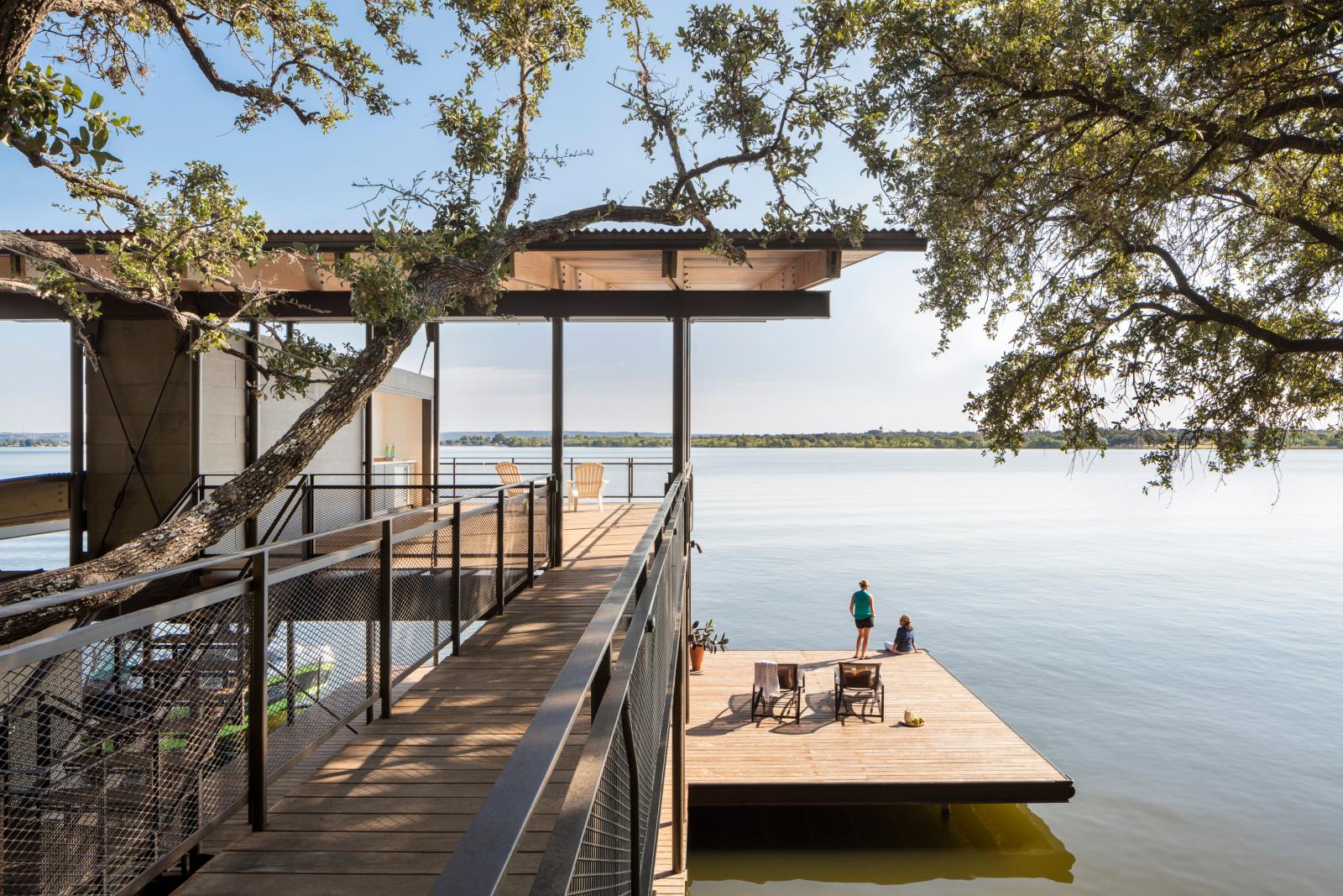 Blue Lake Retreat&#039;s two-story boathouse and swim deck mimic the home’s design, echoing its connection to the land by utilizing a similar bridge to unite the site’s varied landforms.